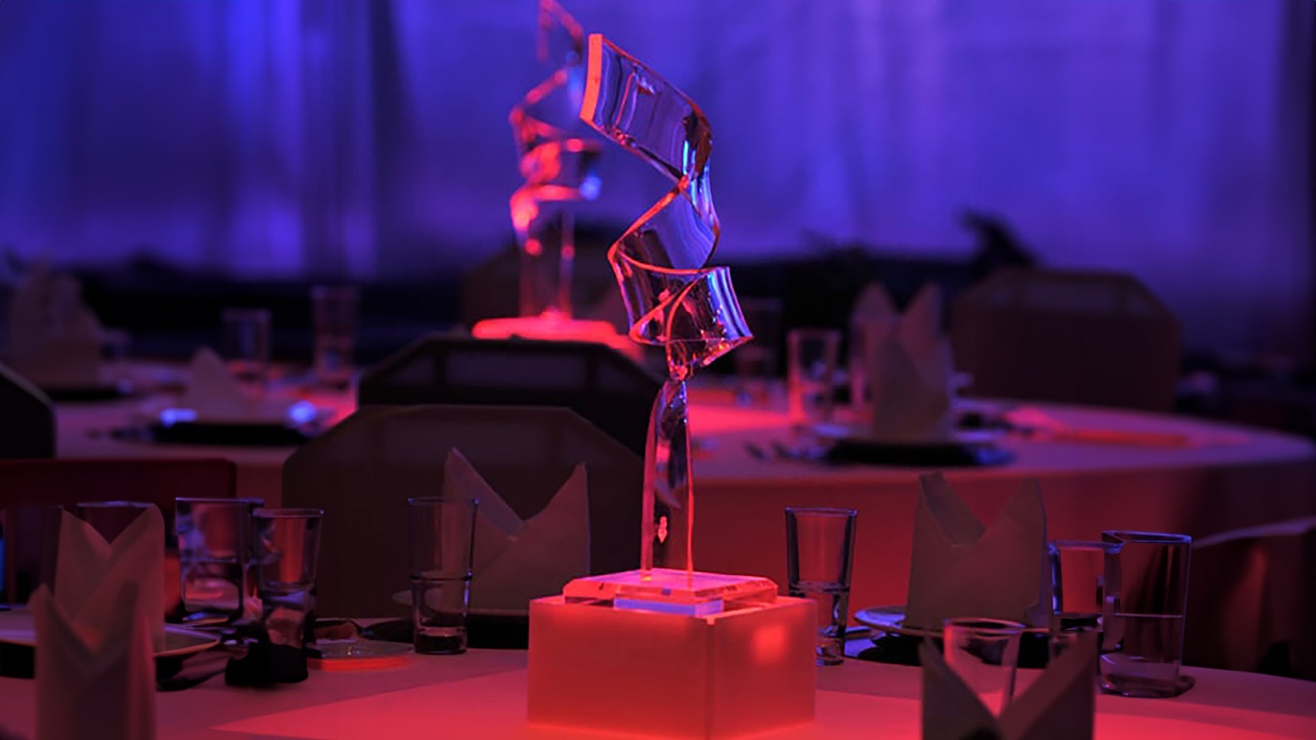 An acrylic ribbon centerpiece illuminated in red in a purple room