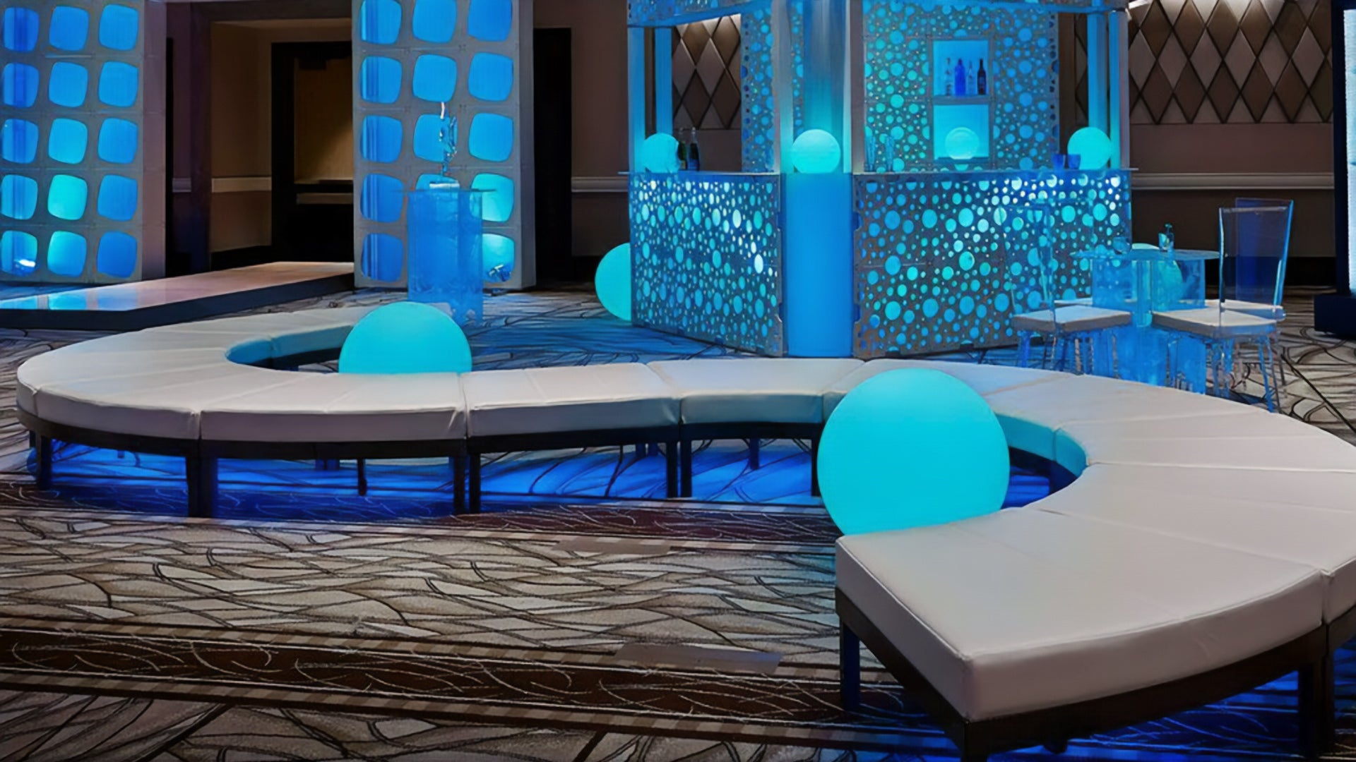 Blue illuminated spheres with a serpentine sofa and decorative towers