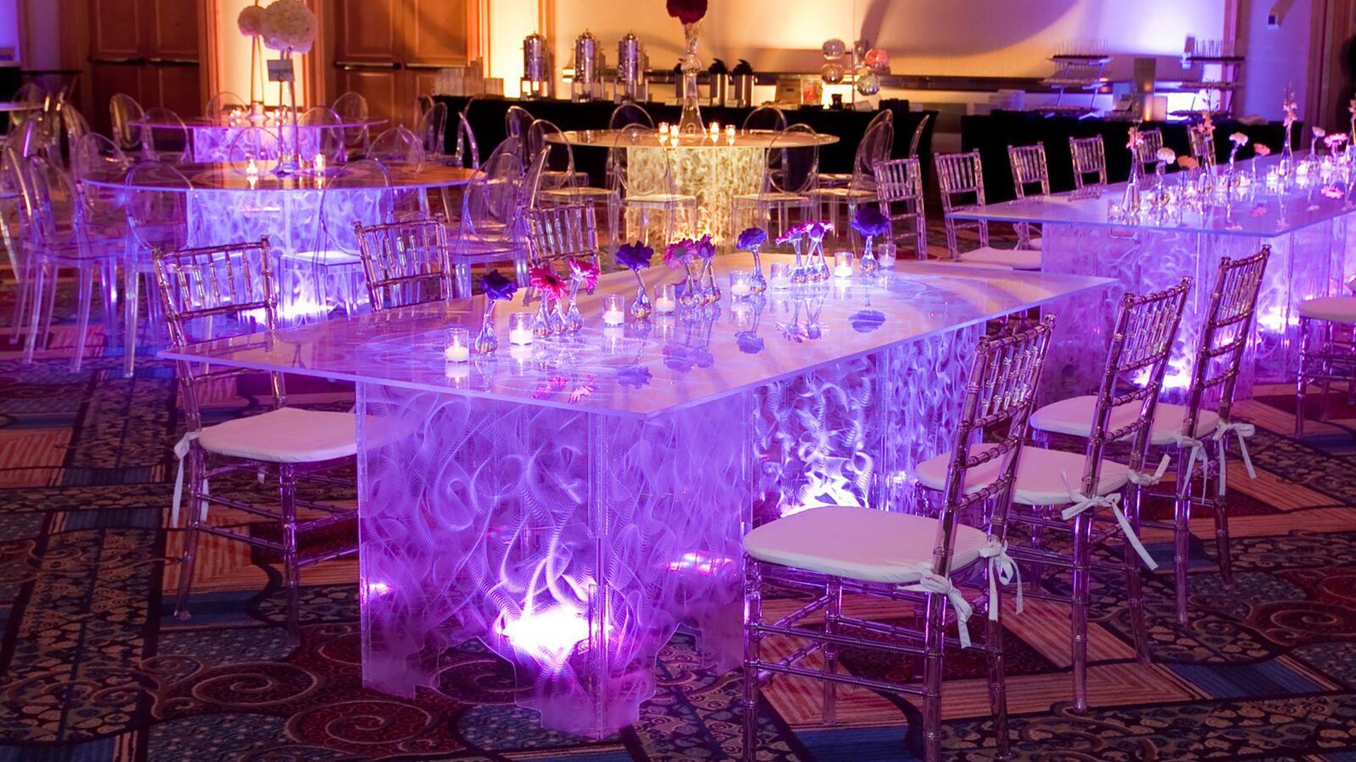 Swirled acrylic dining tables with a purple light in a golden room